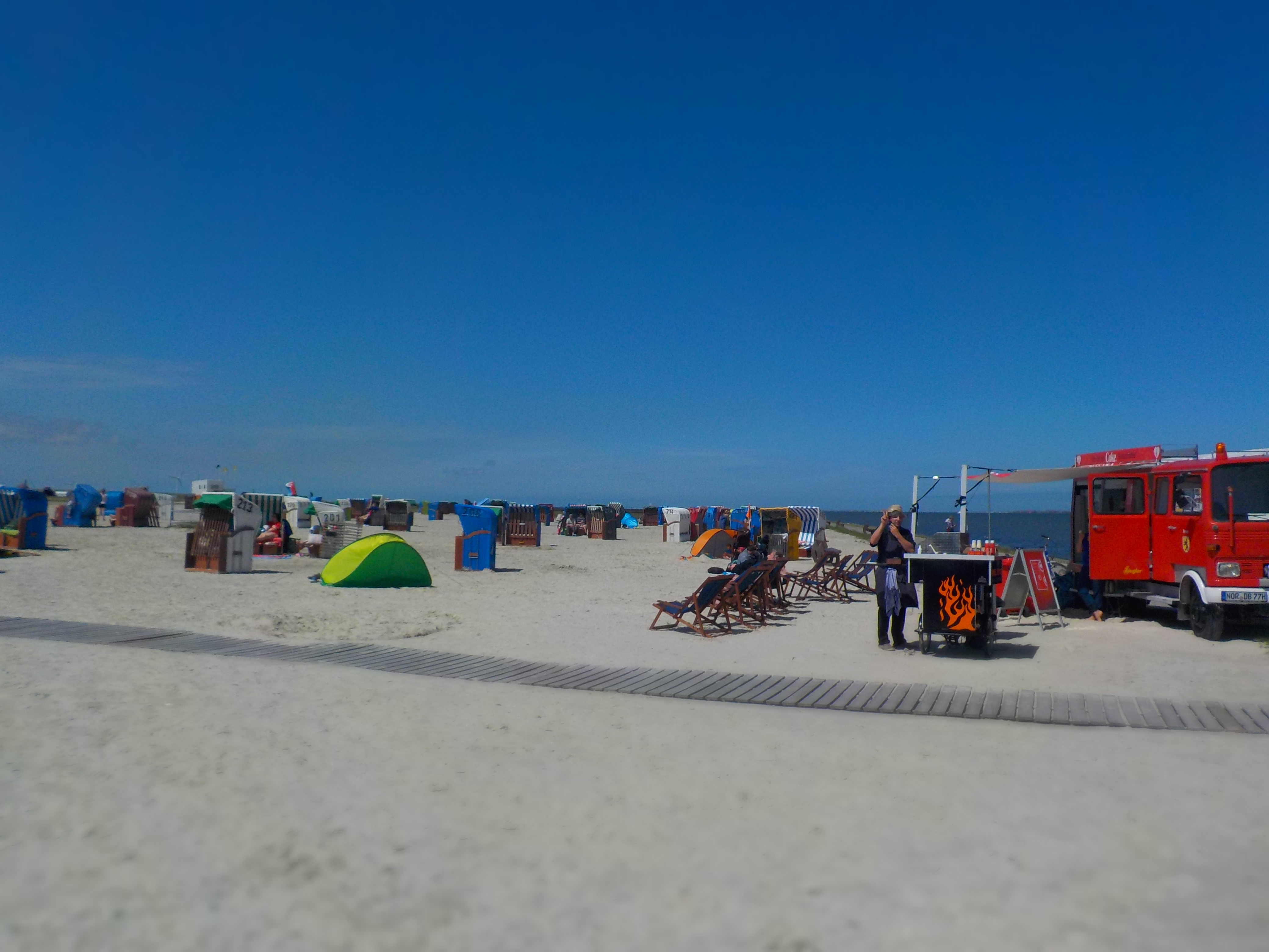 Sandstrand mit bunten Strandkörben unter blauem Himmel